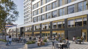 Moderne kantoorgevel aan de H.J.E. Wenckebachweg met mensen op het terras en wandelend op de stoep.